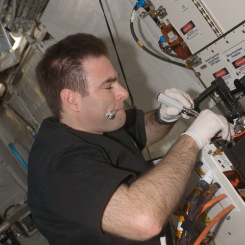 Astronaut installing experiment container in Columbus module